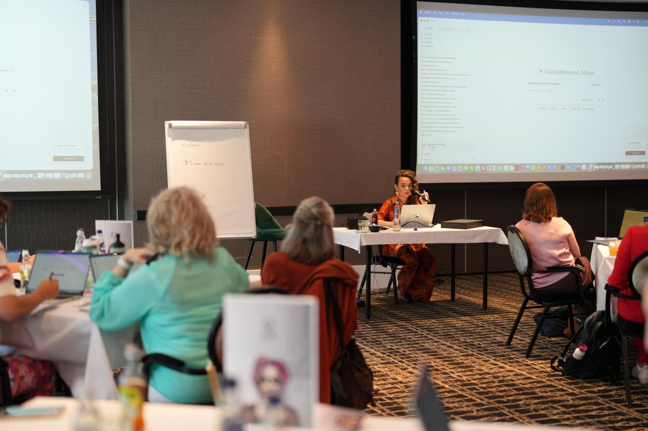 Workshopruimte met deelnemers die luisteren naar een sessie aan het front van de zaal.