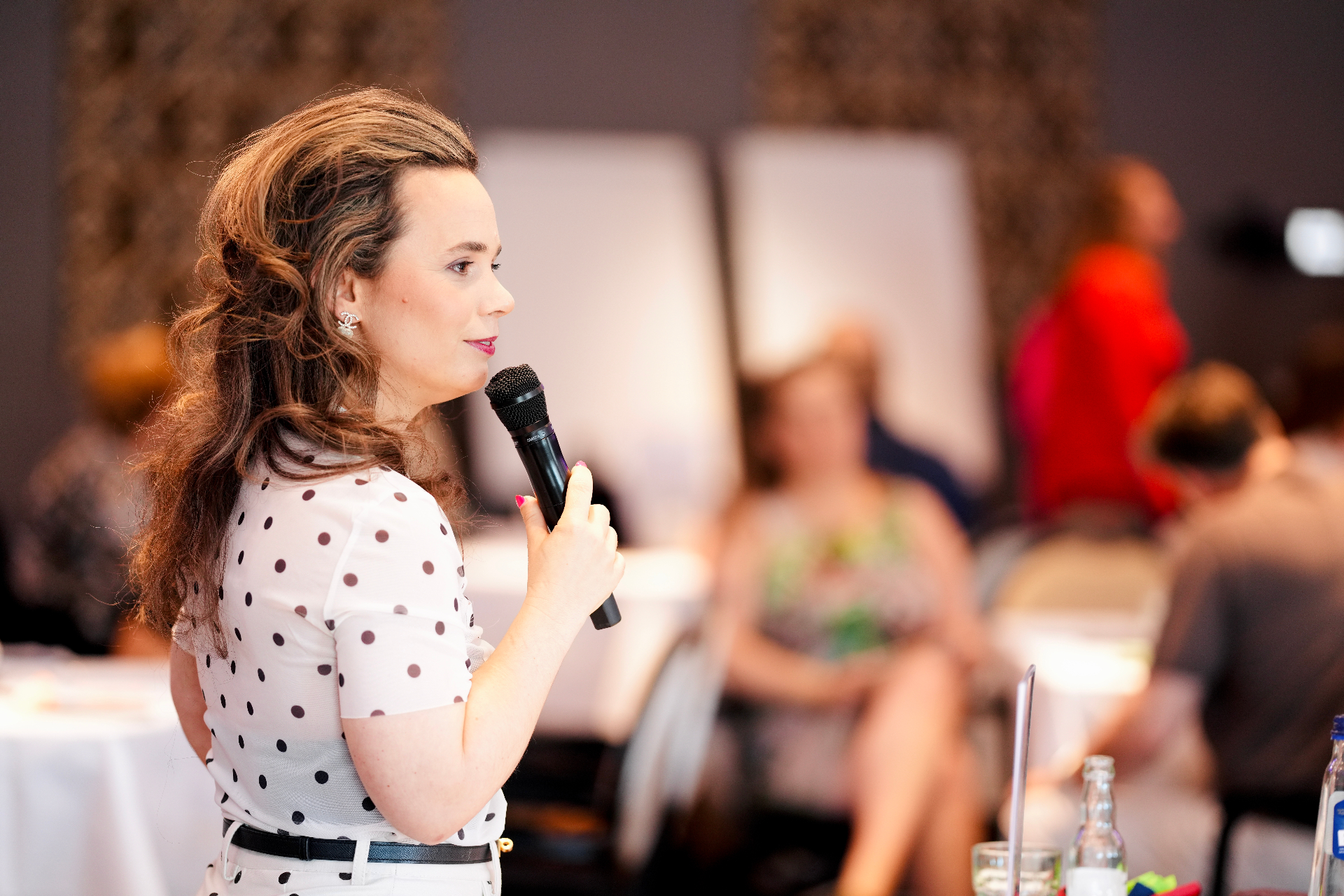 Portret van een spreker met microfoon tijdens een live communitymoment.